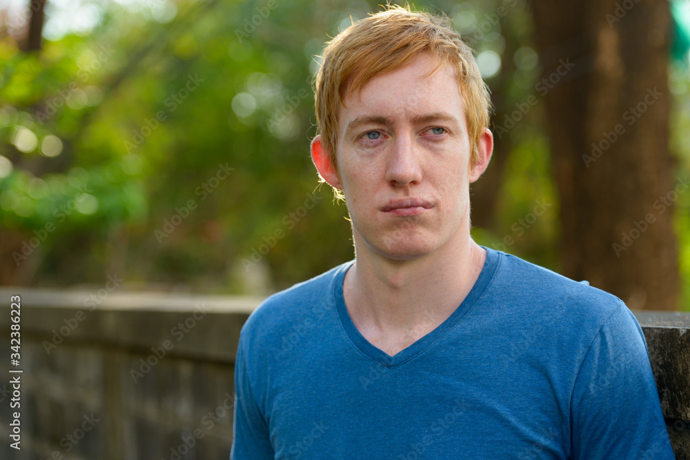 Face of man with red hair thinking in the park Face of man with red hair thinking in the park