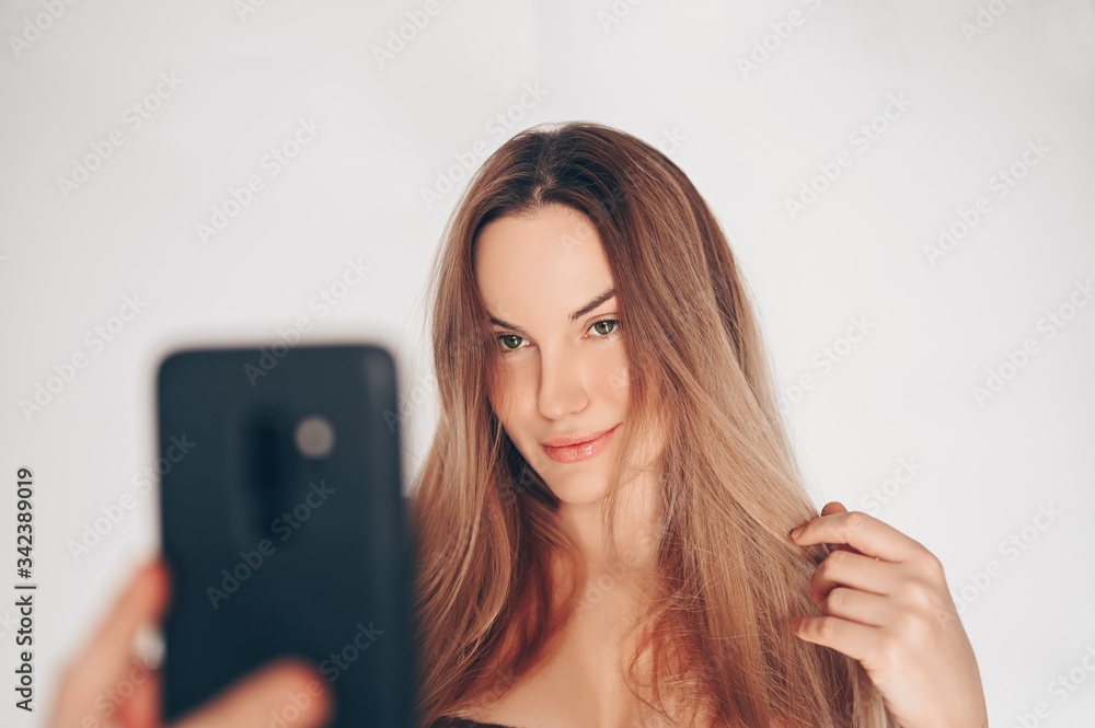 Natural beauty woman with perfect skin making a video call by mobile phone isolated white background. Space for text mockup. Online blogger is live and communicates with followers. Quarantine concept