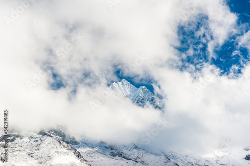 Fresh snow on the top of Mount Kangtega peak hidden in clouds. Trekking in Nepal Himalayas. EBC (Everest base camp trek) trail upper part from Lukla to EBC of Everest trek. Nepal.