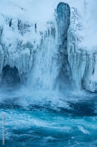 Close up of half frozen Icelandic river Skjalfandafljot flowing over the waterfall Godafoss in Winter