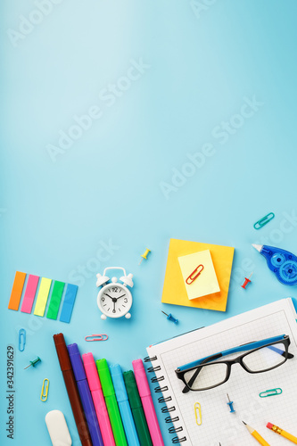 Colorful Stationery items with an alarm clock lie on a blue background.