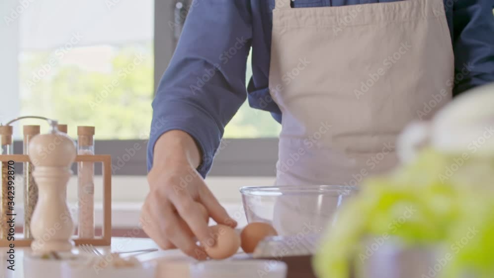Man breaking eggs cooking at home. Food preparation detail. Woman passing eggs to man. Man breaking eggs cooking at home. Food preparation detail. Woman passing eggs to man.