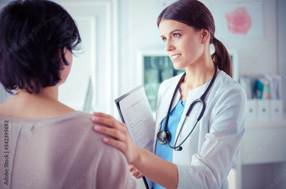 Medical consultation. Female doctor holding a patient by her shoulder, soothing her fear Medical consultation. Female doctor holding a patient by her shoulder, soothing her fear