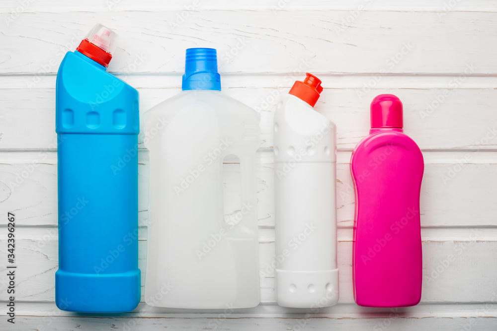 Plastic bottles with chemicals for home cleaning on a white wooden background Plastic bottles with chemicals for home cleaning on a white wooden background