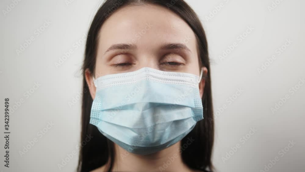Pandemic, portrait of a young european smiling woman wearing protective mask on home isolation. the concept health and safety, N1H1 coronavirus, virus protection Pandemic, portrait of a young european smiling woman wearing protective mask on home isolation. the concept health and safety, N1H1 coronavirus, virus protection