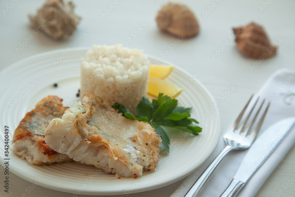 Fried pike fish with rice garnish, parsley and lemon Fried pike fish with rice garnish, parsley and lemon