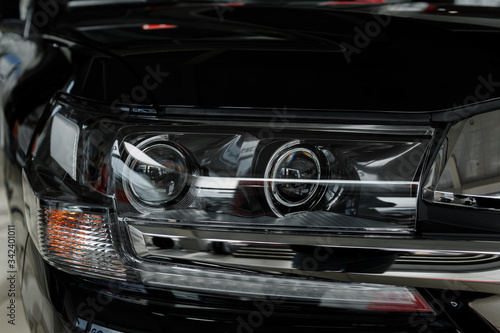 headlight of modern prestigious black car close up. Close up photo of modern car, detail of headlight. Headlight car of a modern luxury technology and auto detail. selective focus. © Andriy Medvediuk