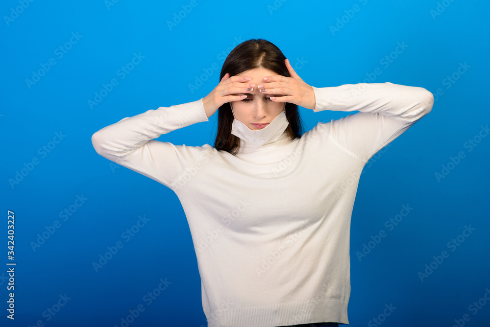 Portrait of a girl in a medical mask, which puts on a rubber glove. Blue background. Copy space. Portrait of a girl in a medical mask, which puts on a rubber glove. Blue background. Copy space.