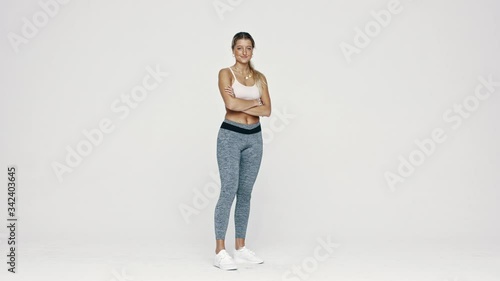 Full length of fitness woman standing over white background. Athletic woman looking at camera and smiling with her arms crossed.
 photo