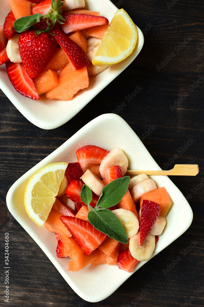 fruit salad with strawberries, yellow melon and banana with lemon. healthy dessert of seasonal fruits. fruit salad with strawberries, yellow melon and banana with lemon. healthy dessert of seasonal fruits.