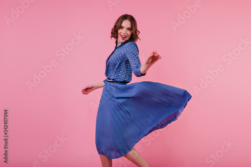 Photo Inspired female model in midi skirt dancing with pleasure on pink background