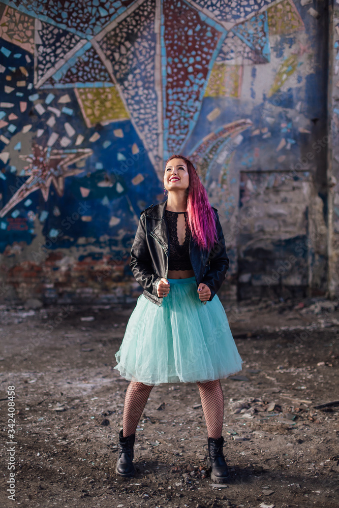 Portrait of a young girl with pink hair standing inside of collapsed building surrounded by ruins