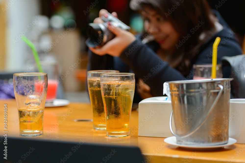 Happy young overweight Asian woman taking picture with beer on table