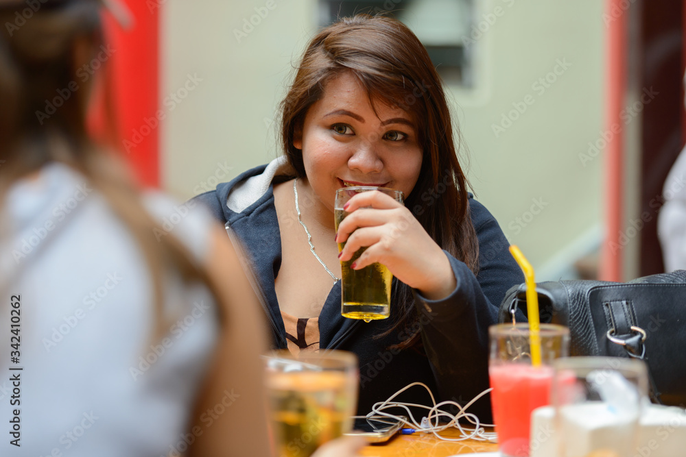 Happy young Asian women as friends hanging out and drinking beer outdoors Happy young Asian women as friends hanging out and drinking beer outdoors