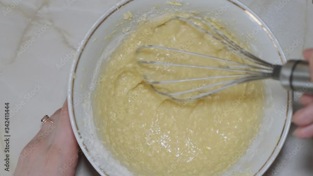 Top down view of female hands mixing cookies dough ingredients with metal whisk. Homemade bakery concept. Top down view of female hands mixing cookies dough ingredients with metal whisk. Homemade bakery concept.