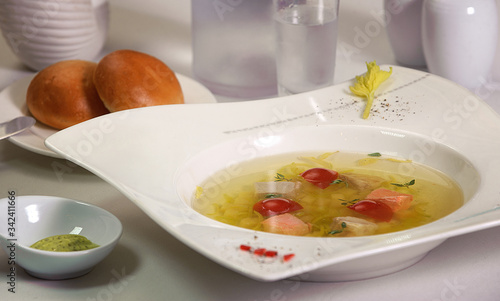 transparent salmon soup with potatoes and red tomato
