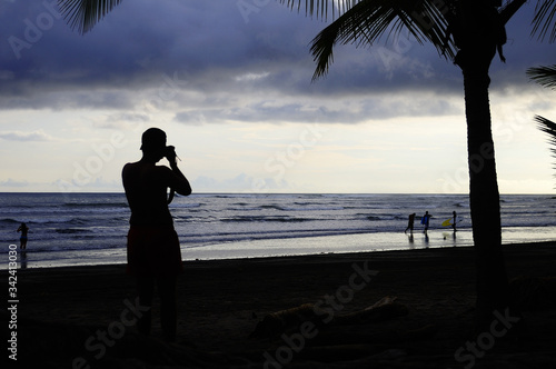 Photographe au coucher de soleil sur une plage tropicale