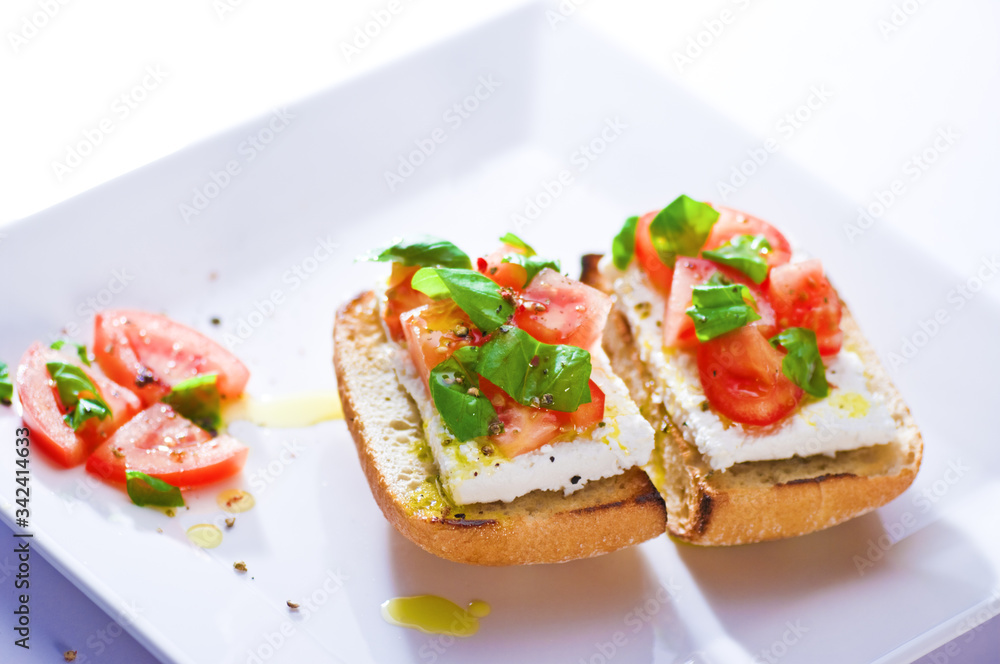 Two sandwiches on a plate, tomato, basil and cheese on bread. Two sandwiches on a plate, tomato, basil and cheese on bread.