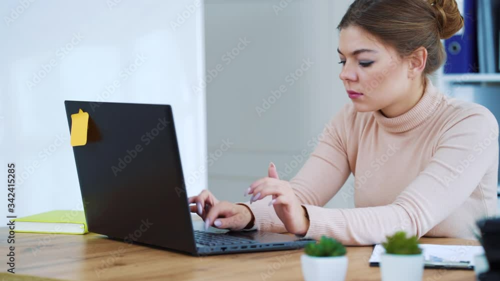 Serious business woman sitting in office and typing on laptop Serious business woman sitting in office and typing on laptop