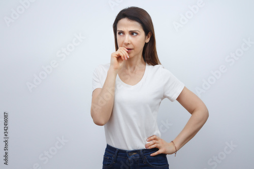 Bild auf Leinwand Giovane donna  con i capelli lisci, indossa una T-Shirt Bianca e un paio di jeans e guarda  con espressione  poco convinta, ,isolata su sfondo bianco