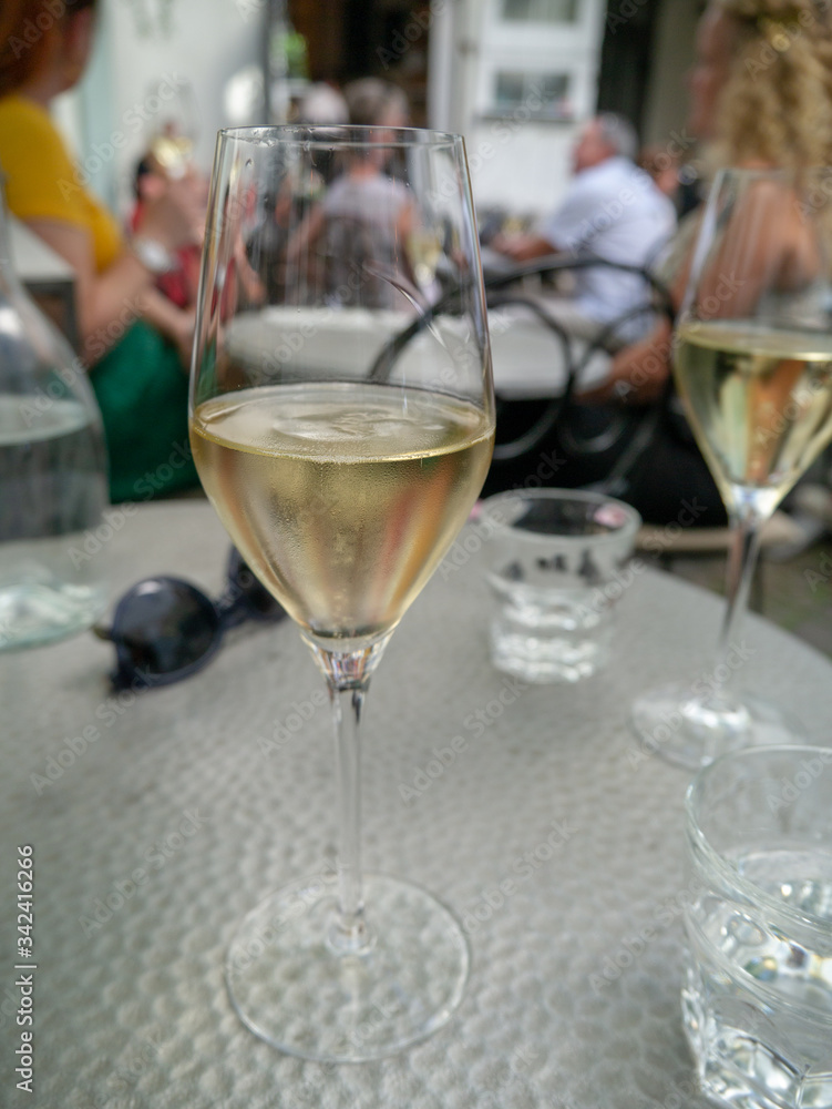 Obraz premium two glasses of champagne on table with glasses and people in the background
