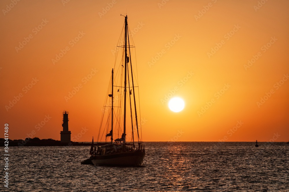 Sunset on the sea with the silhouette of boats and lighthouse. Mediterranean sea Formentera island Spain