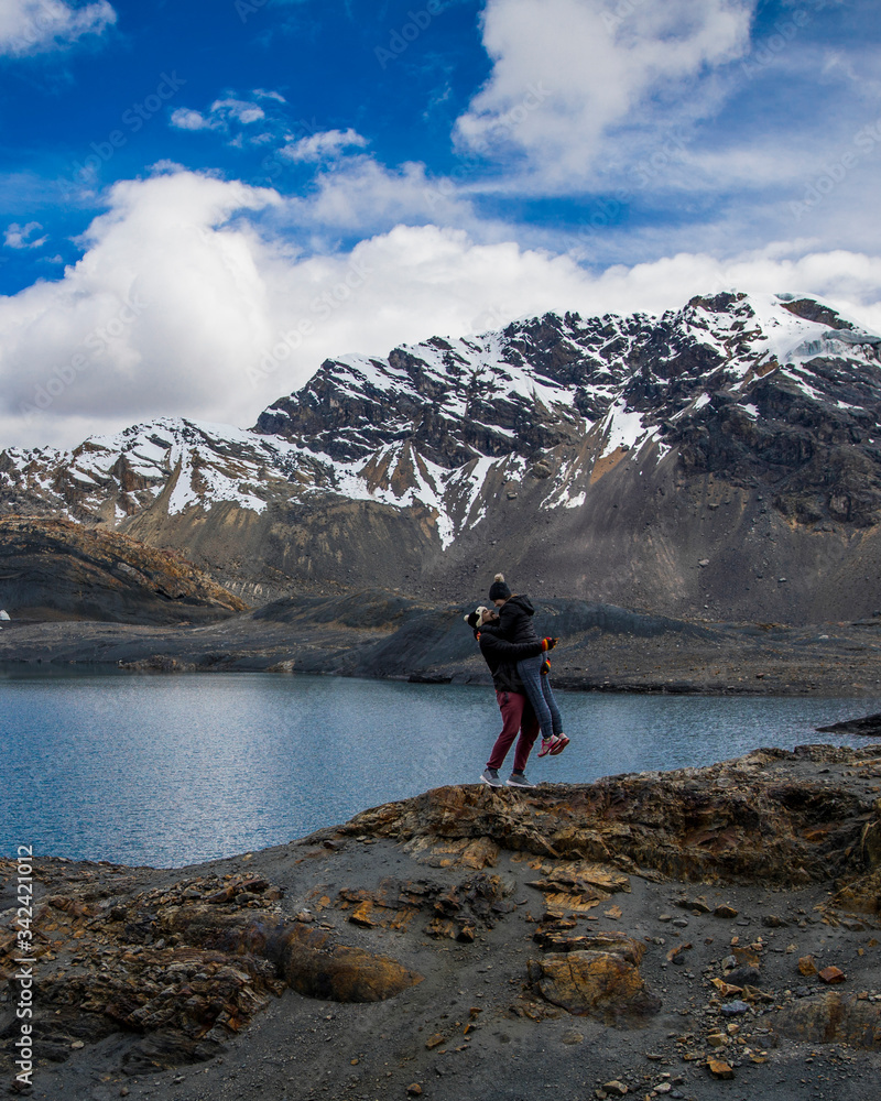 Fototapeta premium Couple by lake and mountain covered in snow