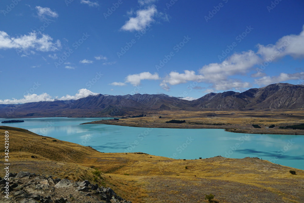 TEKAPU LAKE, NEW ZEALAND - MARCH 11, 2020: View from Mount John towards the lake surrounded with yellow meadows and mountains
