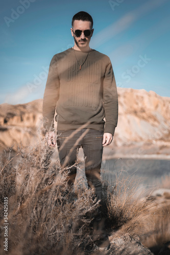 Caucasian man in the middle of the field during sunset, wearing green sweatshirt and sunglasses. © Alex