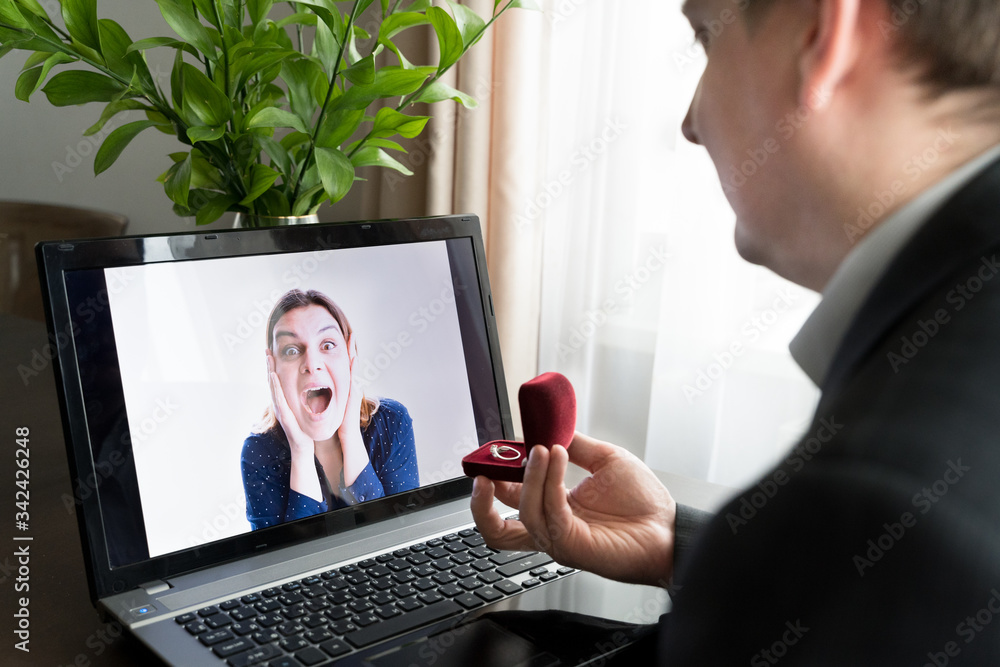 Online video call,marriage proposal to girlfriend.Laptop, computer.Engagement,wedding.Diamond ring in red box. Man:will you marry me.Surprised, shocked woman says yes. Quarantine,coronavirus covid-19 Online video call,marriage proposal to girlfriend.Laptop, computer.Engagement,wedding.Diamond ring in red box. Man:will you marry me.Surprised, shocked woman says yes. Quarantine,coronavirus covid-19