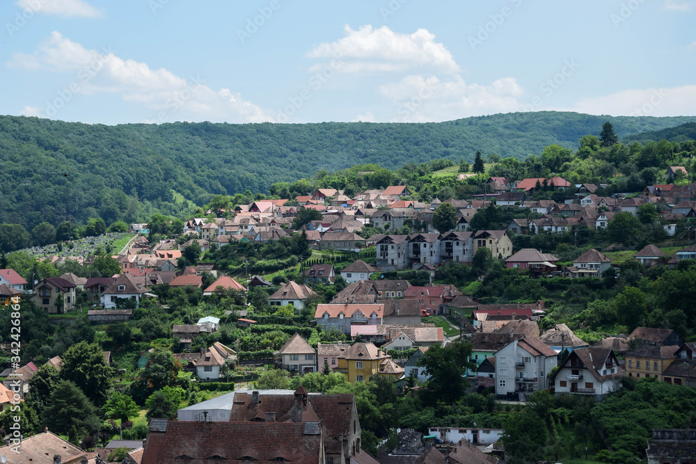Summer panoramic landscape of the old town. Old houses with orange brick roofs. Sighisoara, Mures County, Transylvania, Romania.
