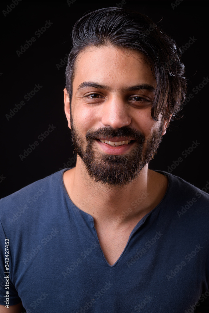 Face of happy handsome bearded Persian man smiling