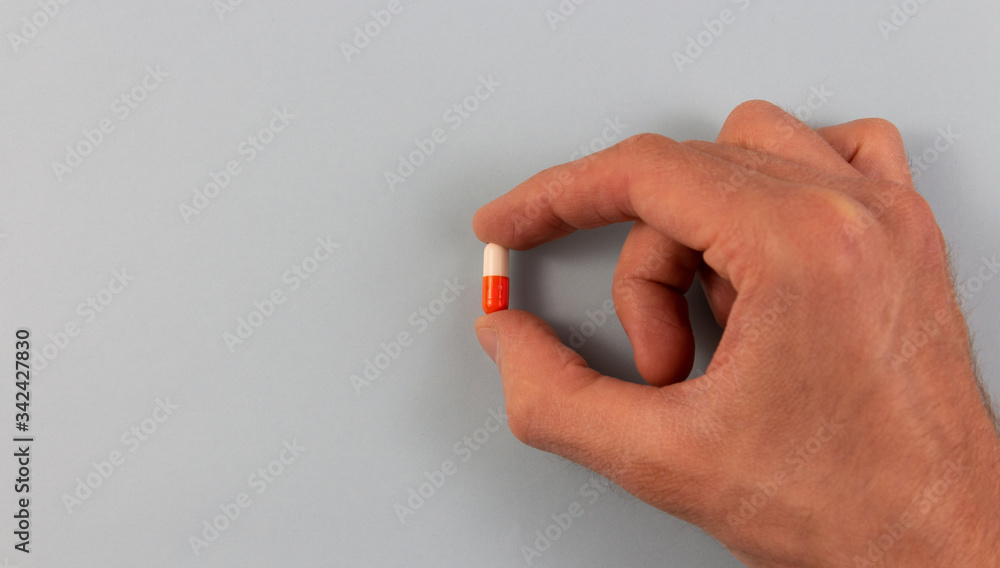 Hand holds a capsule. A tablet or capsule in the hand, palm or fingers of a doctor or nurse.copyspace for text. Hand holds a capsule. A tablet or capsule in the hand, palm or fingers of a doctor or nurse.copyspace for text.