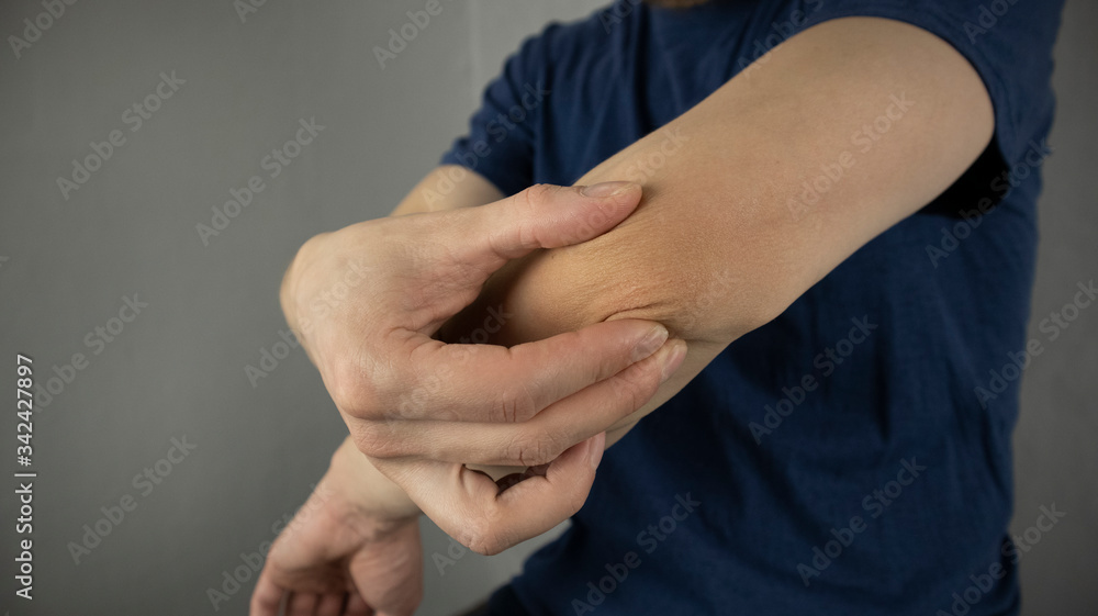 a man makes a self massage of the elbow joint