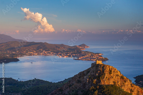 Rocca del Volterraio che domina l'isola d'Elba e domina la baia con il porto di Portoferraio illuminata dal primo sole del mattino