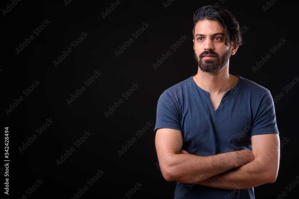 Portrait of handsome bearded Persian man thinking with arms crossed