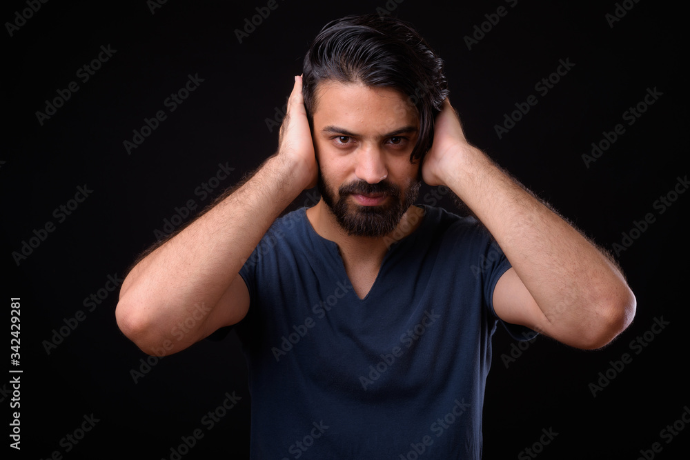 Portrait of handsome bearded Persian man showing hear no evil Portrait of handsome bearded Persian man showing hear no evil