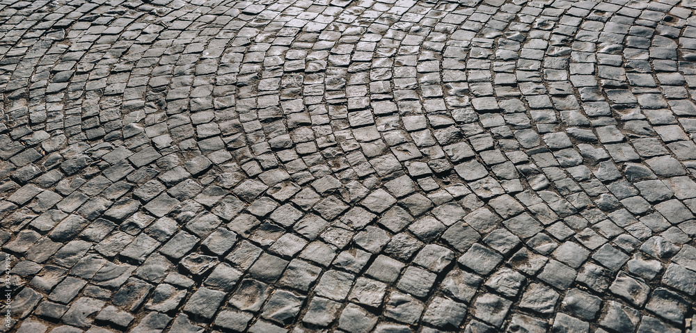 The dark gray paving stones laid out in a semicircle. The texture of the old dark stone. Road surface. Vintage, grunge. The dark gray paving stones laid out in a semicircle. The texture of the old dark stone. Road surface. Vintage, grunge.