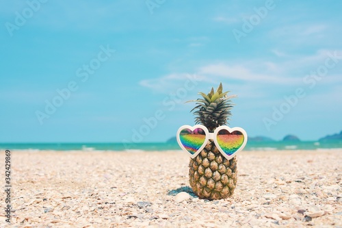 Hipster pineapple with colorful sunglasses on beach.