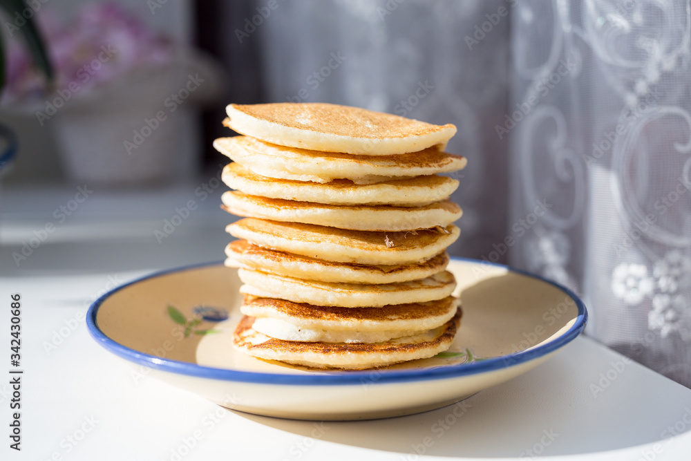 A plate with a homemade pancake on the windowsill. Plate with a breakfast. Sunny morning. Healthy food. A plate with a homemade pancake on the windowsill. Plate with a breakfast. Sunny morning. Healthy food.