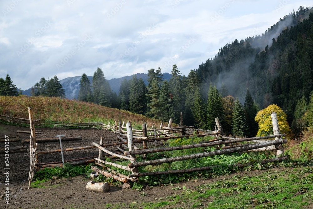 View of wooden fence and field around shepherd's hut in mountains on the route from the Mt. Megruki peak to Atskuri. Borjomi-Kharagauli National Park, Georgia. 