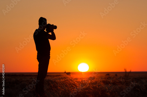 Sunset silhouette photographer taking photos of buck
