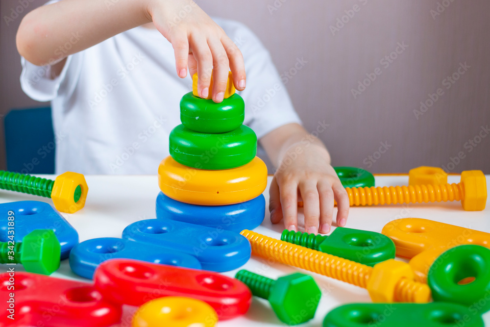 A child plays in a developing designer and builder a multi-colored pyramid of wheels. Children's creativity and learning. Home leisure. A child plays in a developing designer and builder a multi-colored pyramid of wheels. Children's creativity and learning. Home leisure.