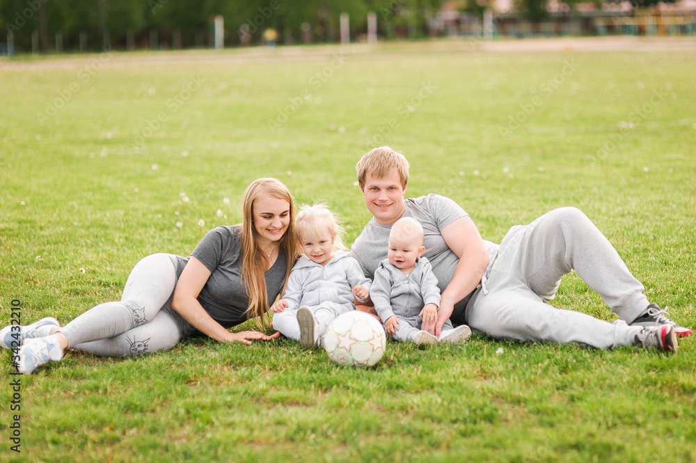 Family Lying On Grass In Park Together. Summer walk, family in nature. Mom, Dad, I am a sports family. Happy family plays soccer with a ball. Family Lying On Grass In Park Together. Summer walk, family in nature. Mom, Dad, I am a sports family. Happy family plays soccer with a ball.
