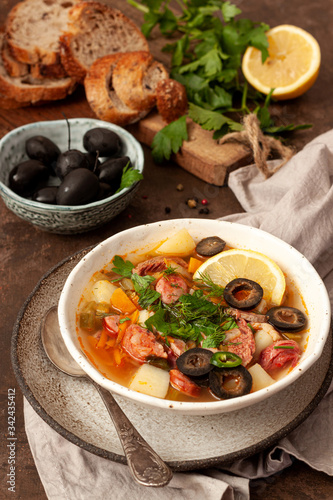 Traditional meat Russian soup solyanka on wooden background