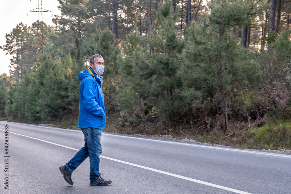 Man in protective mask walking on the rural wooded road. Covid-19 epidemic disease
