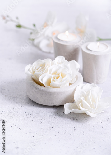 Composition with spa floral scented soap roses and cement gray candles over gray background  copy space. Selective focus. Wabi sabi  minimalism  monochrome background.