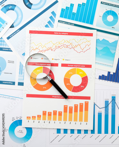 Business chart and magnifier on the desktop. Desktop of a businessman. The concept of analysis and determination of key information in business.