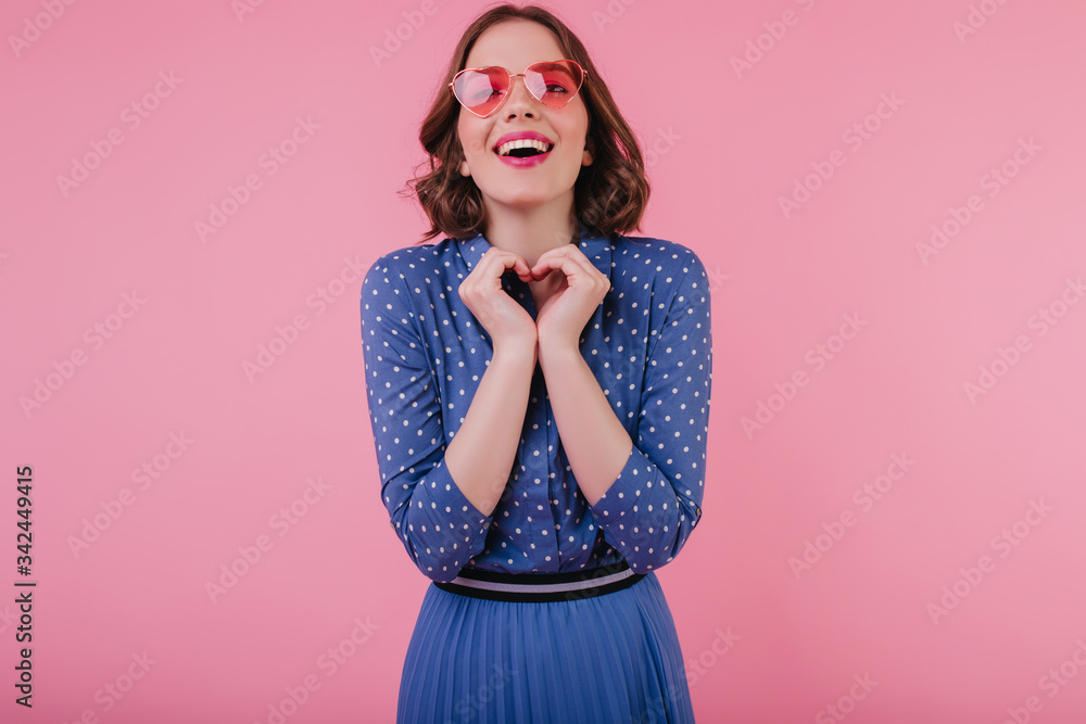 Charming european young woman in blue blouse laughing on pastel background. Enthusiastic white girl in sunglasses having fun while posing in studio. Charming european young woman in blue blouse laughing on pastel background. Enthusiastic white girl in sunglasses having fun while posing in studio.