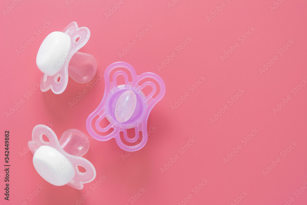 Baby girl pacifier, dummy over pink background. Newborn girl baby abstract flat lay background. Copy space